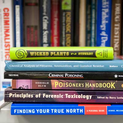 a stack of books related to the study of forensic science, such as chemical analysis of firearms, ammunition and gunshot residue