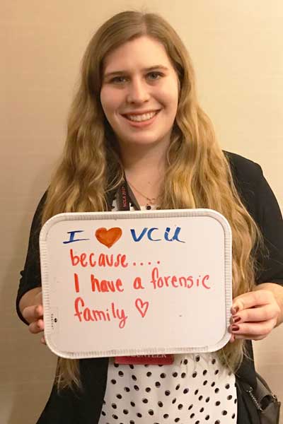 a student holding up a whiteboard that says i love v.c.u. because i have a forensic family